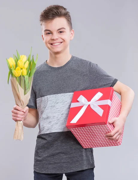 幸福と人々 のコンセプト バレンタインの日を祝う幸せな子 花とギフト ボックスを持つ十代の少年 灰色の背景に黄色のチューリップの花束と少年 — ストック写真