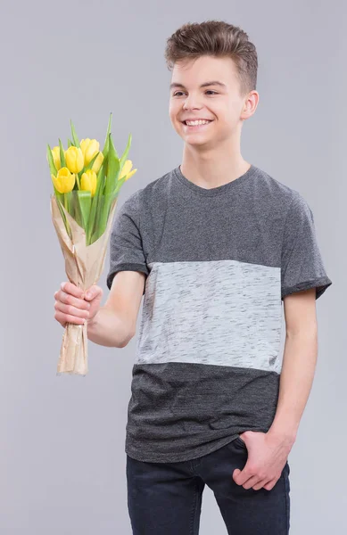 Schöner Teenie Junge Mit Einem Strauß Tulpen Auf Grauem Hintergrund — Stockfoto