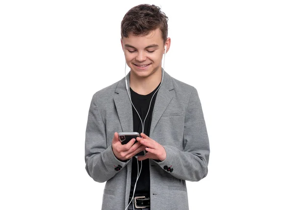 stock image Portrait of Handsome Teen Boy with Mobile Phone and Headphones, isolated on white background. Smiling Child playing on Smartphone and listening to music. Cute modern Teenager in suit.