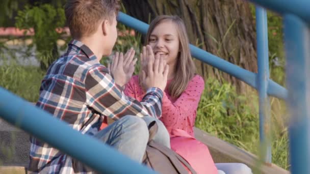 Tiener jongen en meisje zittend op trappen — Stockvideo