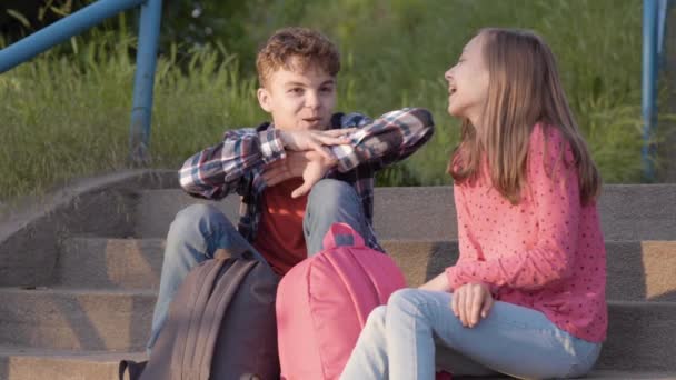 Adolescente chico y chica sentado en escaleras — Vídeo de stock