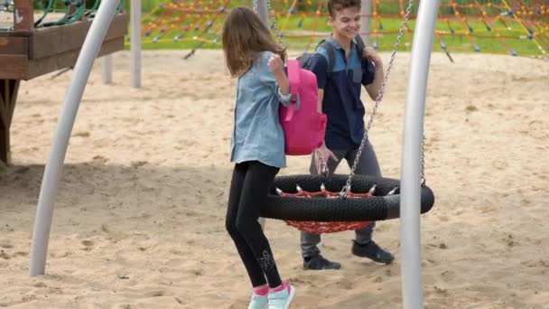 Teen boy and girl on swing — Stock Video