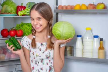 Buzdolabının yanında yemeği olan kız.