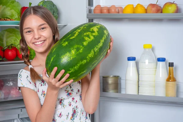 Chica con comida cerca de nevera — Foto de Stock