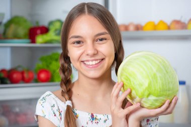 Buzdolabının yanında yemeği olan kız.