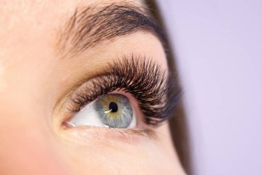 Kirpik uzatma yordamı. Kadın uzun yanlış Eyelashes gözle. Moda gözleri visagein güzellik salonu içinde makro çekim kapatın.