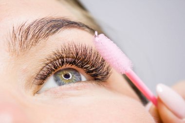 Kirpik uzatma yordamı. Kadın uzun yanlış Eyelashes gözle. Moda gözleri visagein güzellik salonu içinde makro çekim kapatın.