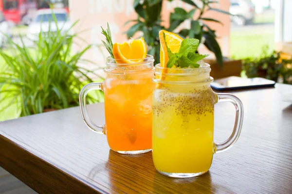 içecekler, insanlar ve yaşam tarzı kavramı - iki taze tropikal sarı ve turuncu Alkolsüz kokteyl ile chia tohum turuncu ve nane dilim ile dekore edilmiş bir mason kavanoza