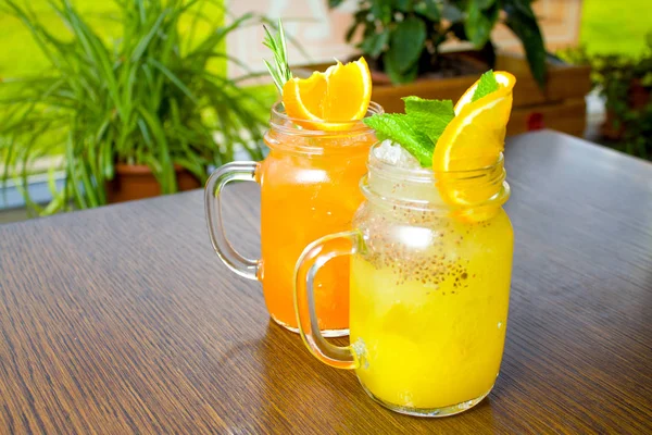 içecekler, insanlar ve yaşam tarzı kavramı - iki taze tropikal sarı ve turuncu Alkolsüz kokteyl ile chia tohum turuncu ve nane dilim ile dekore edilmiş bir mason kavanoza