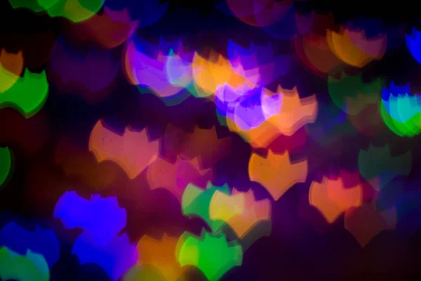 defocused bokeh multicolor lights in shape of bats for halloween background - holidays, decoration and party concept