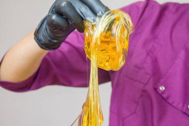 epilasyon ve güzellik kavramı - şeker yapıştırın veya saç Güzellik uzmanı spa salonda siyah eldiven El ile kaldırma için bal balmumu