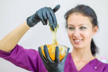 depilasyon ve güzellik kavramı - şeker hamuru veya balmumu bal spa salonunda kozmetolojist siyah eldiven elinde saç çıkarma prosedürü saç için