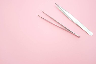 Güzellik ve moda kavramı - kirpik uzatma yordamı için araçlar. Pembe bir arka plan üzerinde iki cımbız. boşaltmak mockup
