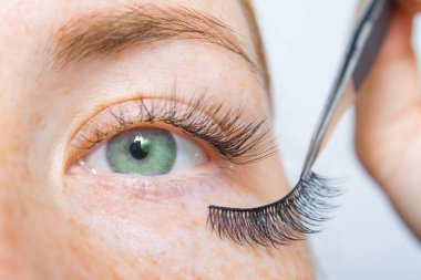 Kirpik Uzatma Tedavi Prosedürleri, Boyama, Kıvırma, Kirpikler için Laminasyon. Uzun suni Kirpikler ile çiller ve yeşil gözlü kızıl saçlı kız. Güzellik ve moda konsepti