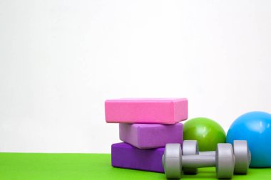 Araçlar için fitness egzersizleri - pembe ve mor blokları, toplar ve halter yeşil mat. metin - jimnastik, stretching, yoga ve spor kavram için boş alan. Seçici odak.
