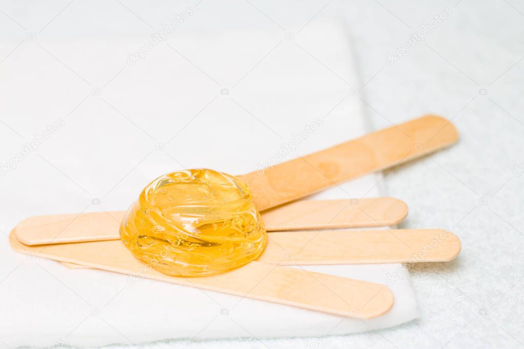 depilation and beauty concept - sugar paste or wax honey for hair removing with wooden waxing spatula sticks
