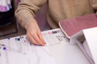 Manikür ve tırnak bakım kavramı. Güzellik Salonu bir kadında renkli test tırnak cilaları farklı renklerle tutar ve boyama için renk seçer.