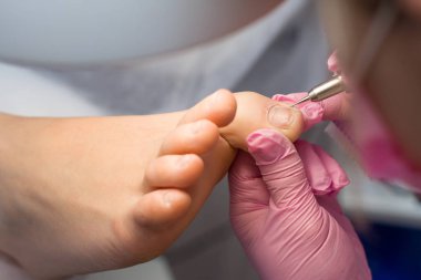 Profesyonel donanım pedikür pembe eldiven ve elektrikli cihaz makine kullanarak. Hastaya tıbbi pedikür yordamı, ayak hastalıkları uzmanı ziyaret etti. Peeling Ayak. Ayak tedavi Spa salonda. Güzellik Salonu