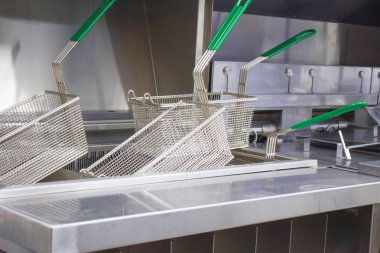 Fritöz patates ve nuggets için. Yeni temiz boş mutfak. Ekipman gıda paslanmaz çelikten yapılmıştır. Fritöz için sepetler. Kavram fast food restoran