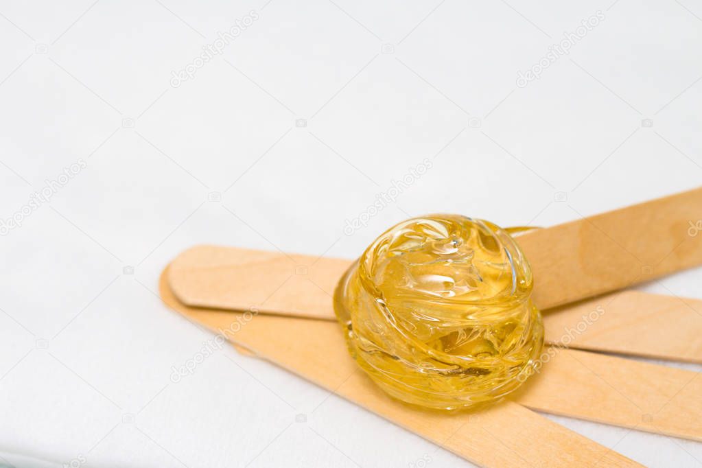 depilation and beauty concept - sugar paste or wax honey for hair removing with wooden waxing spatula sticks