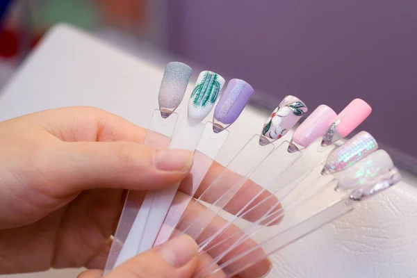 修指甲和指甲护理的概念 美容院里的一个女人拿着不同颜色的彩色测试指甲 选择绘画的颜色 — 图库照片