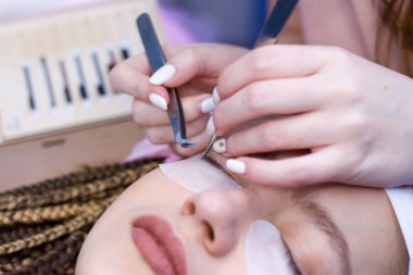Kirpik uzatma yordamı. Kadın uzun yanlış Eyelashes gözle. Twezers elinde beautican bir makro çekim kapatın