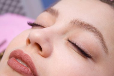 Kirpik uzatma yordamı. Uzun yanlış Eyelashes kadın yüzü. Moda gözleri visagein güzellik salonu içinde makro çekim kapatın.