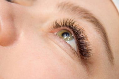 Kirpik uzatma yordamı. Kadın uzun yanlış Eyelashes gözle. Moda gözleri visagein güzellik salonu içinde makro çekim kapatın.