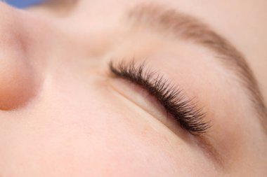 Kirpik uzatma yordamı. Kadın uzun yanlış Eyelashes gözle. Moda gözleri visagein güzellik salonu içinde makro çekim kapatın.