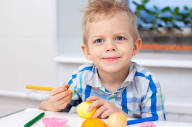 Küçük sarışın çocuk Paskalya ve resim yumurta için hazırlanıyor. Renkli işaretleri. Paskalya ve tatil kavramı.