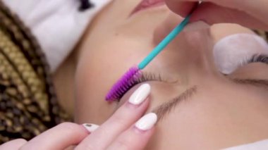 Kirpik uzatma prosedürü. Uzun yanlış kirpik ile kadın göz. Güzellik salonunda moda gözleri closeup makro çekim. El güzellik uzmanı. Bir fırça ile kirpik sihirbaz fırçalar müşterinin kirpik