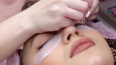 Kirpik uzatma prosedürü. Uzun yanlış kirpik ile kadın göz. Güzellik salonunda moda gözler Visage bir çekim makro çekim. Cımbız ile Hands güzellik