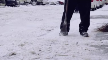 Servis şirketi evin avlusunda ve kar ve buzdan kaldırımlar temizler. Üniformalı iki adam çalışıyor, elinde kürek tutuyor..