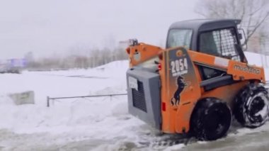 St-Petersburg, Rusya, 08 Feb 2019-hizmet şirketi ev ve kar ve buzdan kaldırımlar bahçesinde temizler. Bobcat veya Skid Loader kar-kaldırma küçük traktör kova ile yol temizler