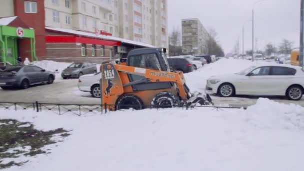 サンクトペテルブルク ロシア 2019 サービス会社は 家の庭と雪と氷から歩道を清掃します ボブキャットまたはスキッドローダースノー除去小型トラクターは バケツで道路をきれいにします — ストック動画