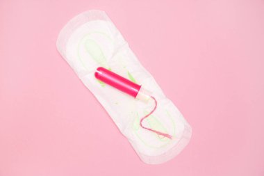 bir pamuk tampon ile pembe bir arka plan üzerinde adet yastık üzerinde pembe applicartor. Kız döngüsü dönem kavramı. Kadın gün hijyen koruma. Üstten Görünüm, düz yatıyordu. boşaltmak