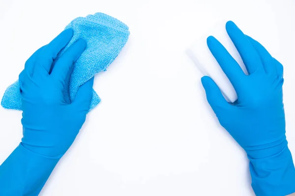 Vrouw hand in blauwe rubberen handschoenen houdt rag en spons op witte achtergrond. schoonmaak en regelmatig opruimen concept. Bovenaanzicht. plat lag. copyspase — Stockfoto