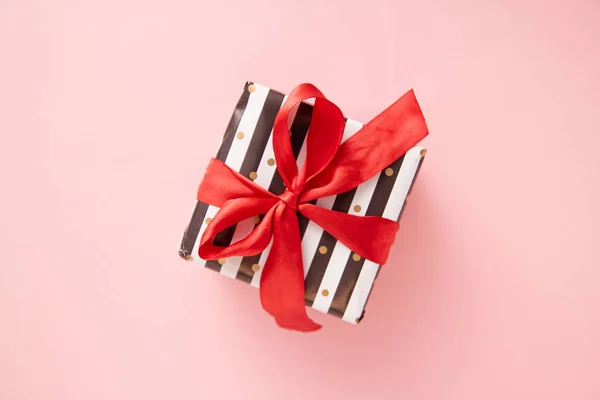 礼品或礼物盒在白色和黑色条纹与红色丝带弓隔离在粉红色的桌面视图。最低限度的平面组合销售, 生日, 母亲节或圣诞节。复制空间 — 图库照片