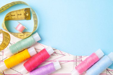 Çok renkli iplik bobinleri ve mavi arka plan üzerinde ölçüm bandı. Dikiş malzemeleri, desen ve aksesuarlar, dikiş, dikiş, nakış. boşaltmak. düz yatıyordu, en iyi görünümü