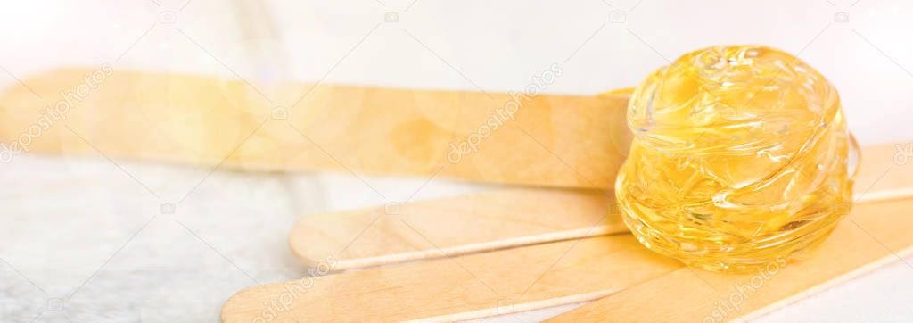 extra wide banner background with sugar paste or wax honey for hair removing and wooden waxing spatula sticks - depilation and beauty salon concept.