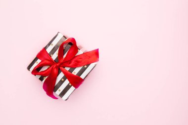 Hediye veya siyah ve beyaz çizgili pembe tablo üstten görünüm üzerinde izole kırmızı şerit yay ile mevcut kutusunda. En az düz kompozisyon satışlar, doğum günü, anneler günü ya da Noel için yatıyordu. boşaltmak