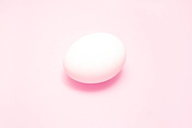 Beyaz paskalya yumurtası pembe arka planda ortada. Tasarım, görsel sanat, minimalizm