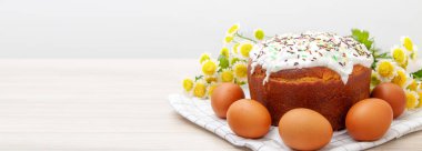 Paskalya pastası ve arka planda sarı çiçek açan renkli yumurtaların olduğu geniş pankart. Tatil yemeği ve paskalya konsepti. Metin için kopyala.