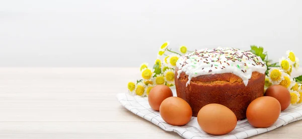 wide banner with Easter cake and colored eggs yellow flower blossoms on background. Holiday food and easter concept. Copyspase for text.