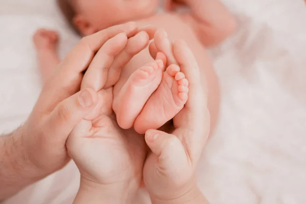 Embarazo, maternidad, preparación y expectativa maternidad, dando a luz concepto. Los pies recién nacidos en manos de los padres — Foto de Stock