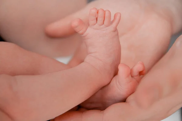 Embarazo, maternidad, preparación y expectativa maternidad, dando a luz concepto. Los pies recién nacidos en manos de los padres — Foto de Stock