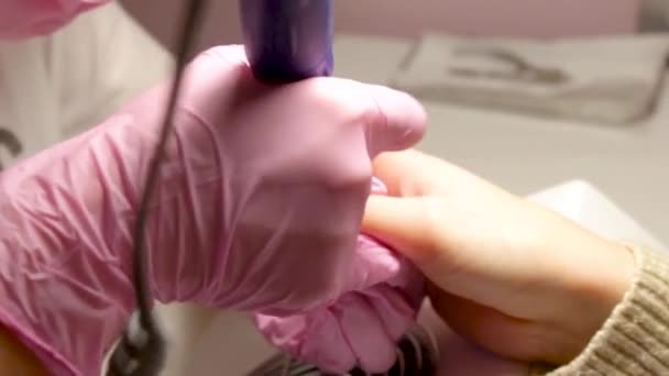 采用电动设备机进行五金修算 在涂指甲油之前 要准备指甲的程序 在粉红色的手套和客户端的指甲美甲手 美容院的女人 — 图库视频影像