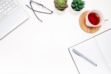Çalışma alanı, gözlüklü dizüstü bilgisayar, çizim defteri, sulu, beyaz arka planda bir fincan çay. Üst kattaki ofis masasında yatıyordu. Serbest çalışan bir iş yeri. kopyalama alanı