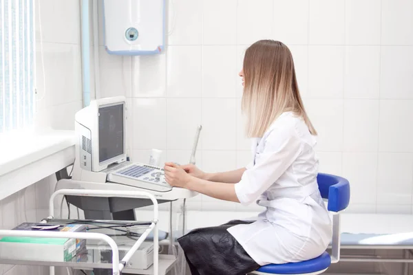 Die blonde Ärztin in weißer Uniform arbeitet im Krankenhaus an einem Ultraschallscanner. Diagnostik, Sonographie und Gesundheitskonzept. Kopierschutz — Stockfoto