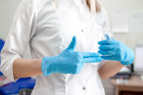Професійний лікар-гінеколог у білих ультрафіолетово-блакитних рукавичках робить гінекологічний знак пальця. Кабінет з медичним обладнанням на фоні. Здоров'я жінки і концепція вагітності — стокове фото